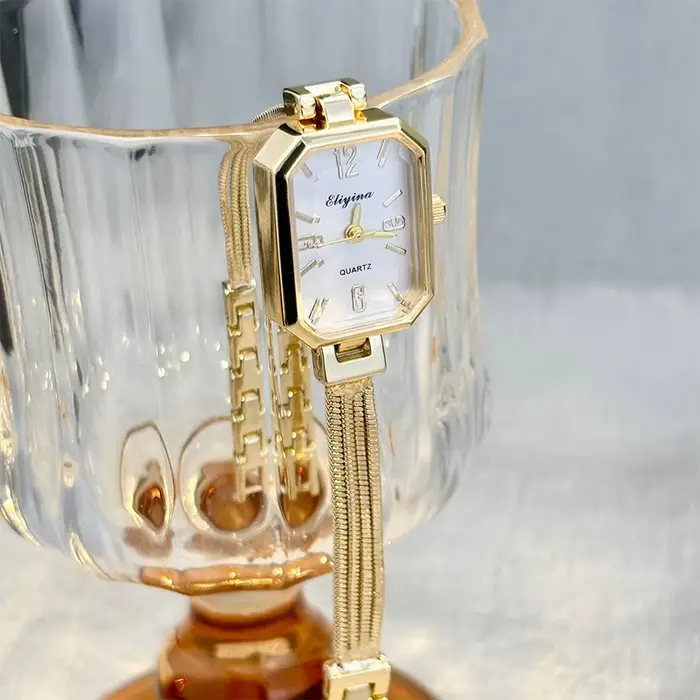 Montre-bracelet rectangulaire dorée pour femme avec chaînes à pampilles, un accessoire délicat