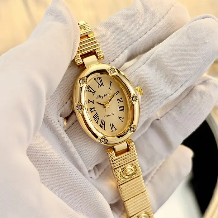 Montre dorée élégante pour femme avec cadran ovale, motifs étoiles et bracelet E-Charmed